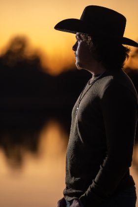 Silhouette of a cowboy at sunset by the pond