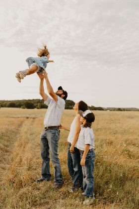 Dad tossing his baby in the air in a prairie field