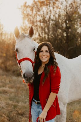 Woman in red jacket with her white horse at golden hour, Oklahoma portrait photography by Taylor McClain