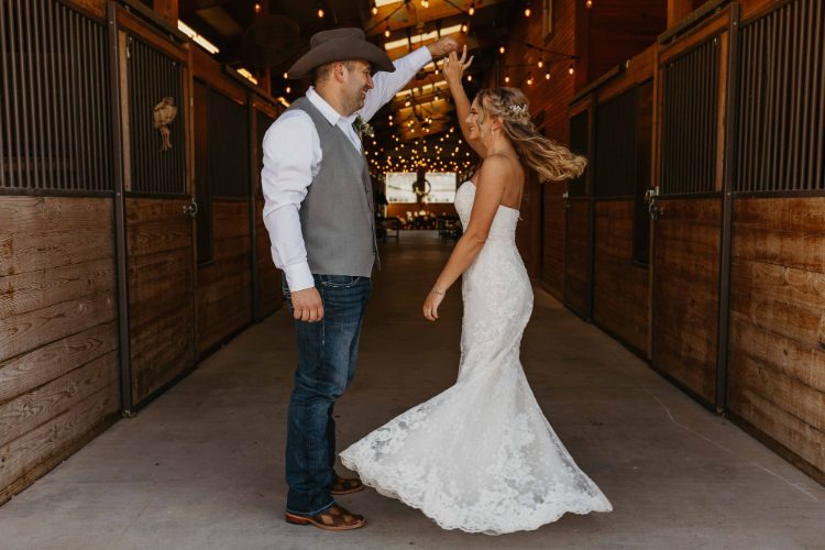 Bride and groom dancing in a horse barn aisle