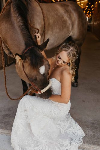 Bride in lace gown with her horse in the barn