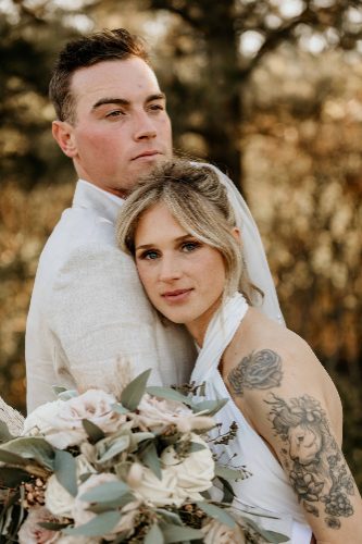 Bride resting her head on the groom with bouquet