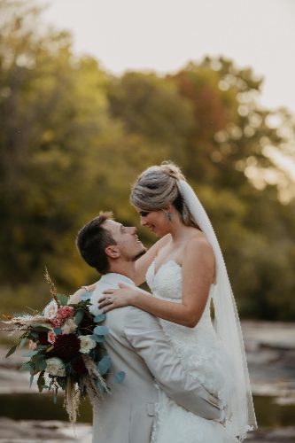 Groom lifting bride by the water