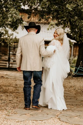 Groom in cowboy hat walking with bride outdoors